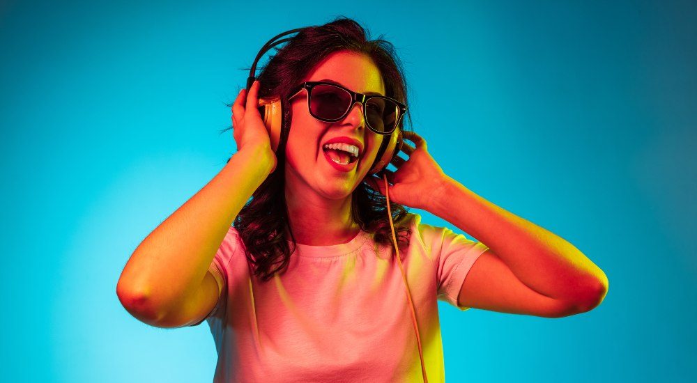 mujer joven feliz con gafas de sol escuchando música con audífonos